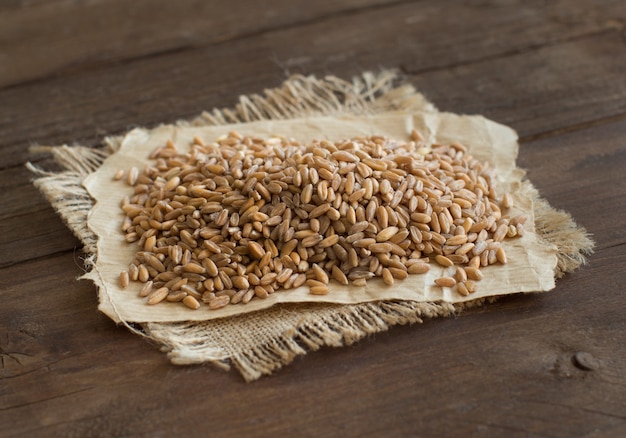 Pile of whole unpolished spelt close up on wood