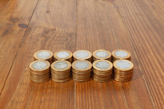 A pile with a lot of Real brazilian money coins stacked on a wood table