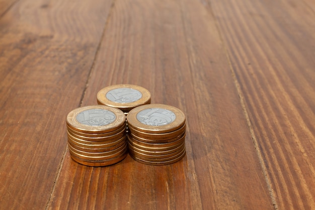 Photo a pile with a lot of real brazilian money coins stacked on a wood table