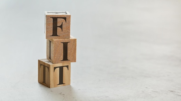 Pile with three wooden cubes - letters FIT on them, space for more text / images on right side.