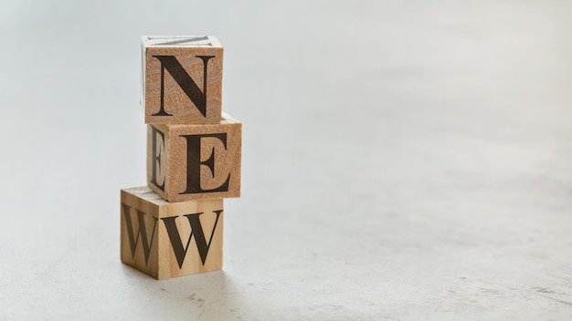 Pile with three wooden cubes - letters NEW on them, space for more text / images on right side.