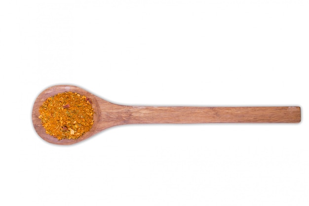 A pile of a yellow spice mix for chicken  on wooden spoon isolated on white . Spices consist paprika onion garlic mustard coriander thyme celery turmeric fennel black pepper