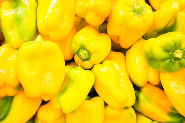 Pile of yellow sweet bell peppers at vegetable market. Can be used as food background