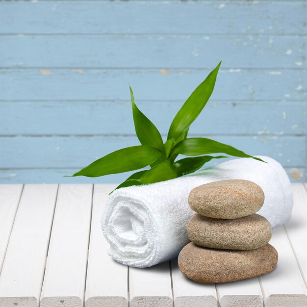 Pile of zen stones with fluffy towel on wooden background