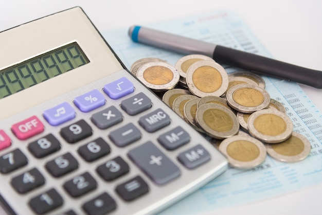 Piles of coins and calculator with pen