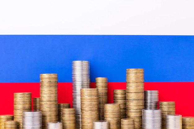 Piles of golden and silver coins on the of russian flag