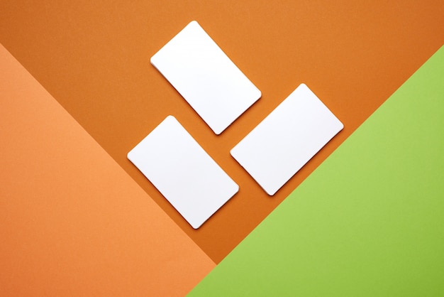 Piles of white paper blank business cards on orange-green background