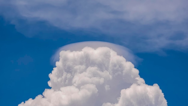 Облако Pileus на белом облаке Cumulonimbus Congestus на фоне голубого неба