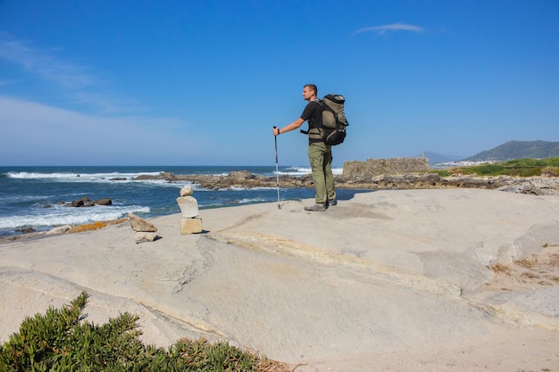 Pilgrim on ocean coast Portugal Camino del Norte Tourist with backpack and walking sticks