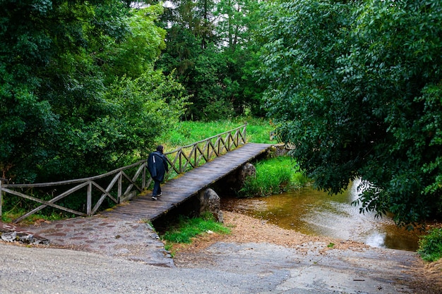 Pilgrim walking on the wooden bridge over the river along the Camino de Santiago