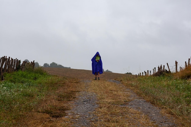 Пилигрим в водонепроницаемой куртке проверяет свой смартфон во время Chemin du Puy France.