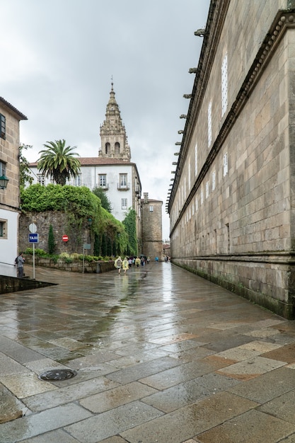 サンティアゴデコンポステーラの旧市街の雨の日の通りを歩いている巡礼者と観光客