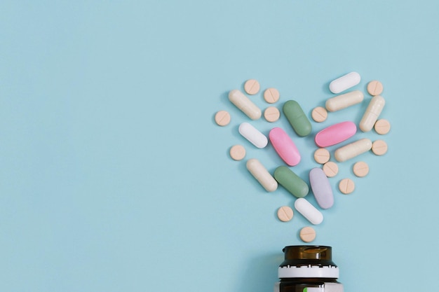 Bottiglia di pillola che versa fuori pillole colorate su compresse di superficie su un tavolo sfondo blu vista dall'alto farmaco concetto di assistenza sanitaria medica