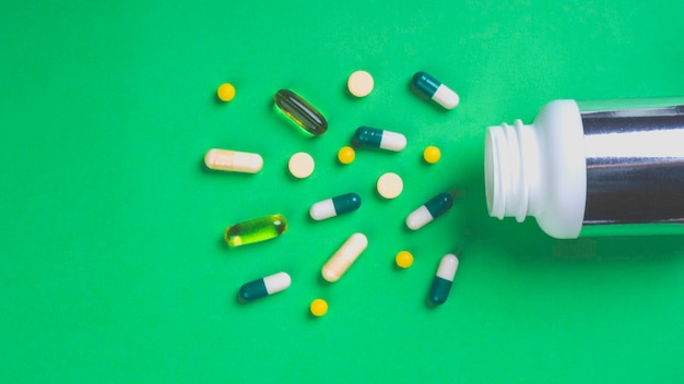 Photo pill bottle with colorful pills on the green background
