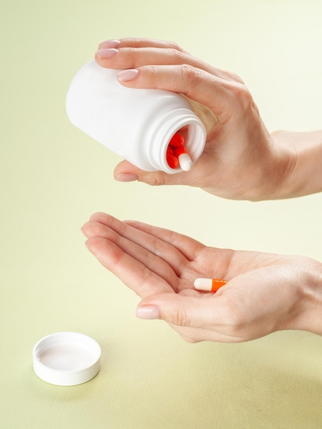 Photo pill bottle in a woman's hand empty white bottle for packaging medicines mockup space for logo and text