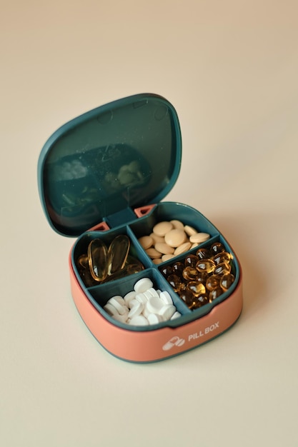 Pill box contains four different types of pills Pillbox lies on beige background