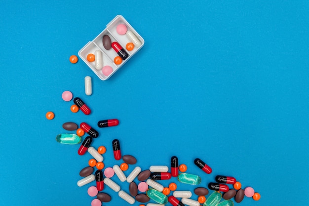 Pill dispenser with multicolored pills on blue background