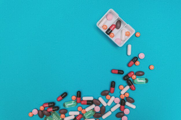 Диспенсер для таблеток с разноцветными таблетками на синем фоне