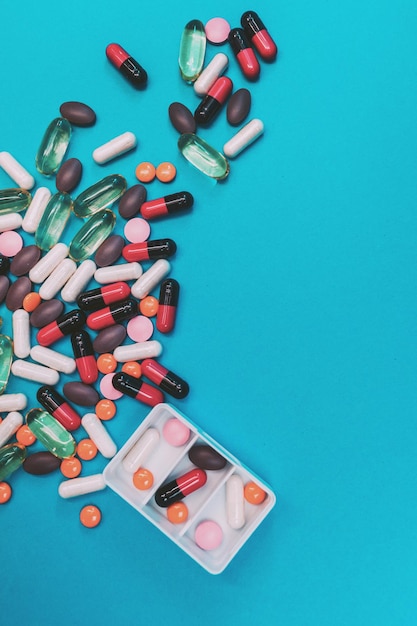 Pill dispenser with multicolored pills on blue background