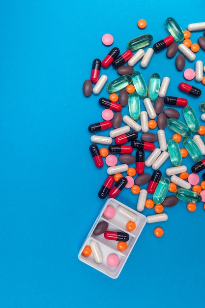 Pill dispenser with multicolored pills on blue background