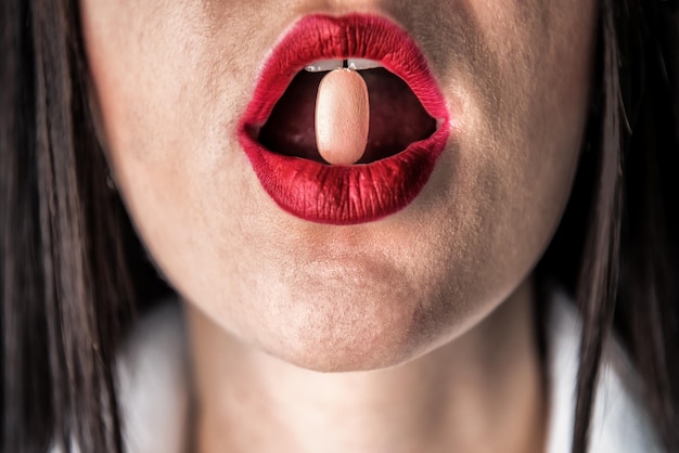 Pill in red female lips. Healthcare and medical industry