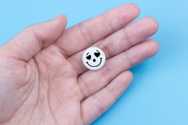 Pill with heart eyes in hands on a blue background Viagra concept