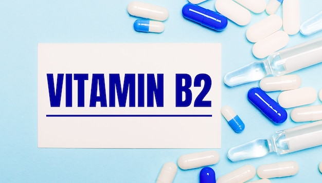Pillen, ampullen en een witte kaart met de tekst VITAMIN B2 op een lichtblauwe achtergrond. medisch concept