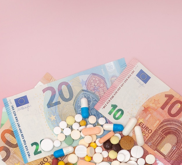 pillen en euro op een roze achtergrond met kopie ruimte. Zachte focus. Concept geneeskunde, geld en gezondheid.