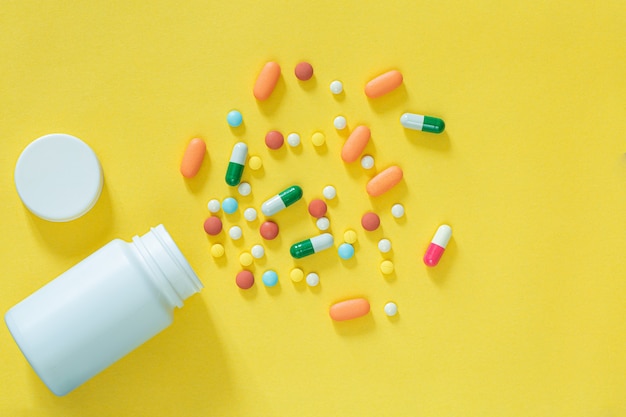 Pillen en medicijnflessen op een gele achtergrond Allerlei soorten medicijnen om in te stoppen