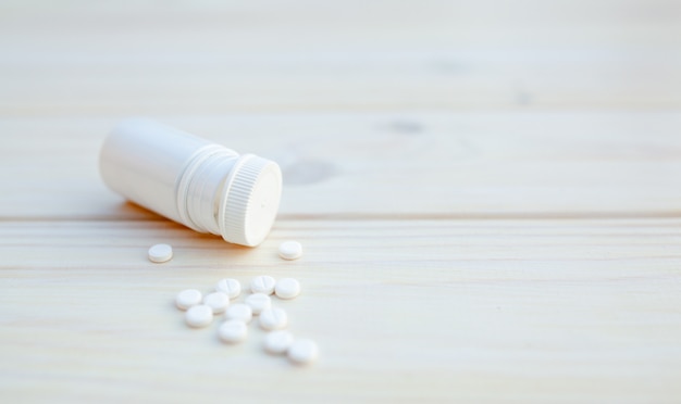 Pillen en pillenfles op witte houten achtergrond