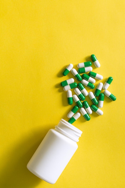 Foto pillen en pillenflessen op gele achtergrond, bruine medische glazen medicijnfles en wat pillen in de buurt