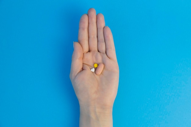 Pillen in de vorm van een hart liggen op de palm Op een blauwe achtergrond Uitzicht van bovenaf