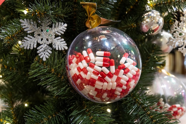 Pillen in transparante bal hangen aan de kerstboom een medisch cadeau voor het nieuwe jaar het concept van geneeskunde en gezondheid