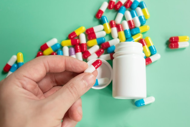 Pillen medicijnen of supplementen in de hand van een man close-up op groene achtergrond