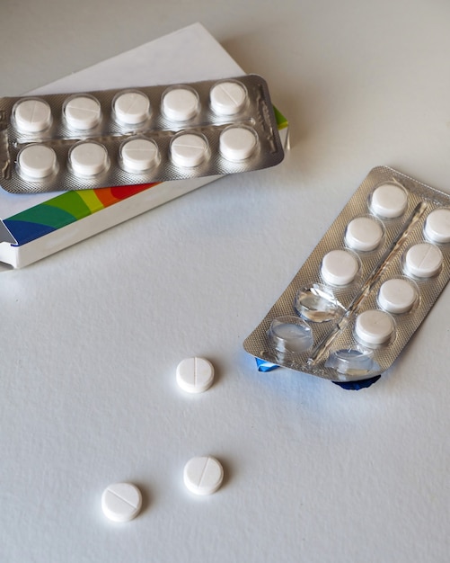 Pillen op een witte achtergrond, een verstrooiing en een doos met medicijnen voor de behandeling van virussen