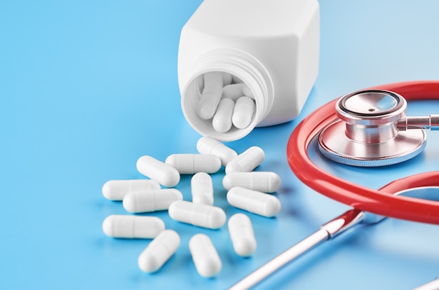 Pillen tabletten capsules close-up. Op een blauwe achtergrond, een potje geneeskunde. Op een blauwe achtergrond, een potje geneeskunde en een stethoscoop.