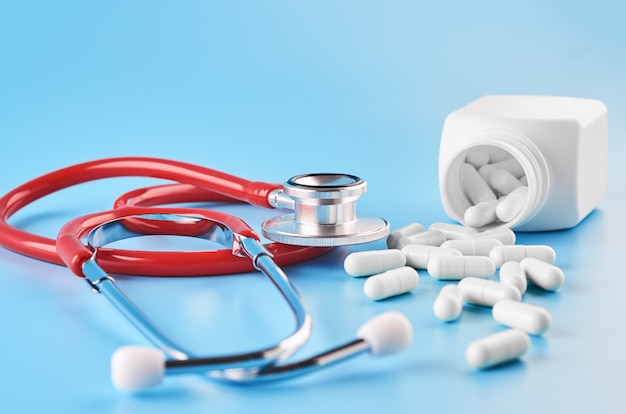 Pillen tabletten capsules close-up. Op een blauwe achtergrond, een potje geneeskunde. Op een blauwe achtergrond, een potje geneeskunde en een stethoscoop.