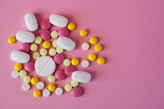 Pillen van verschillende kleuren en vormen op een roze achtergrond
