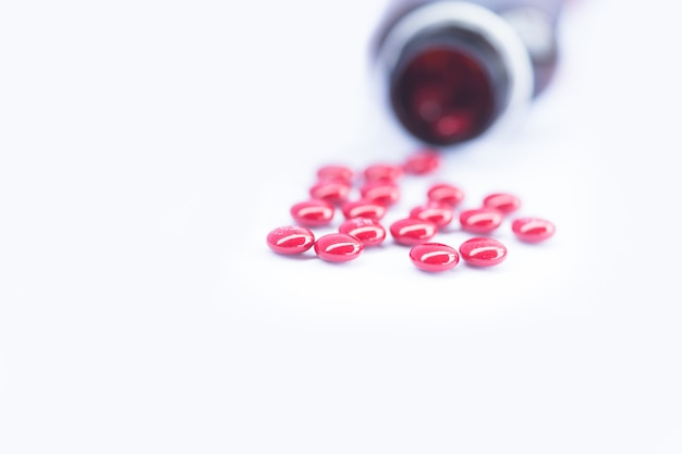Pillenfles met Rode Vitaminen binnen op witte achtergrond.