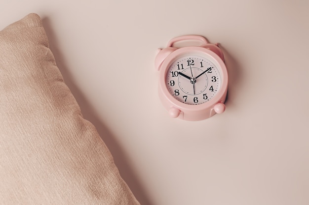 Pillow and alarm clock on a beige background. Healthy restful sleep concept.