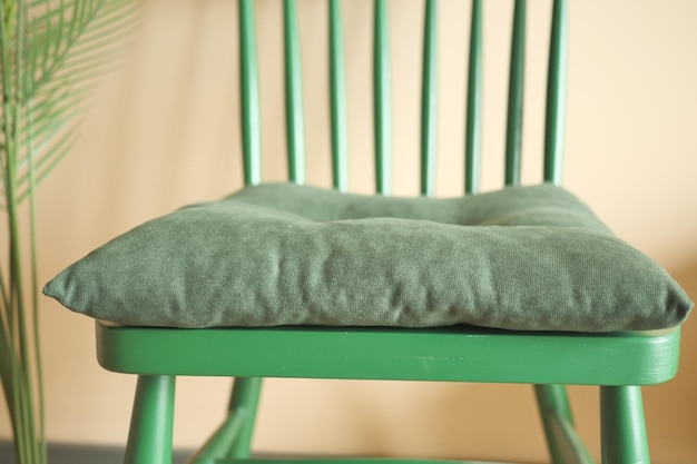 Pillow on a green wooden chair in a room