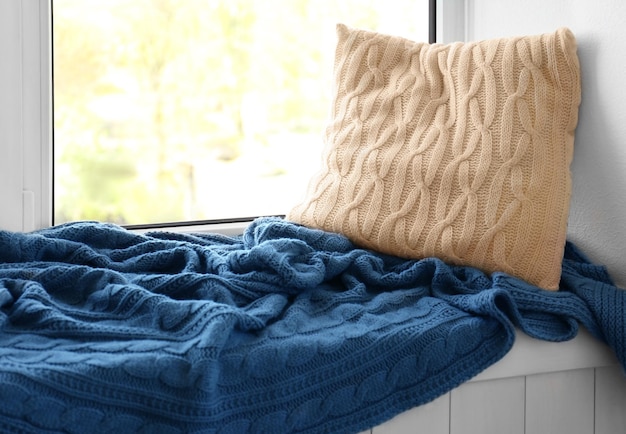 Pillow and warm knitted plaid on a window sill