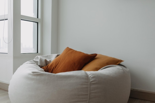 Pillows and beanbag sofa in white room next to the window