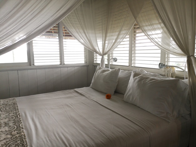 Photo pillows on a white canopy bed with curtains