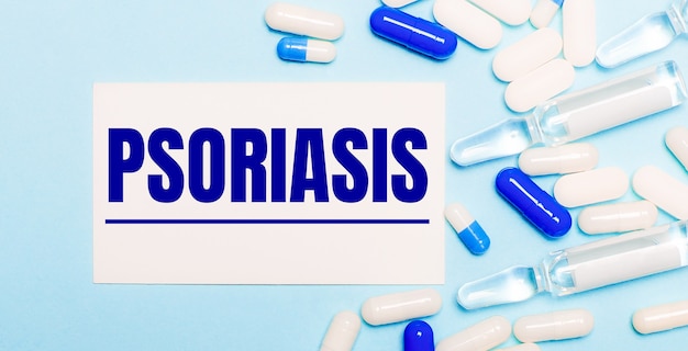 밝은 파란색 표면에 PSORIASIS라는 텍스트가있는 알약, 앰플 및 흰색 카드