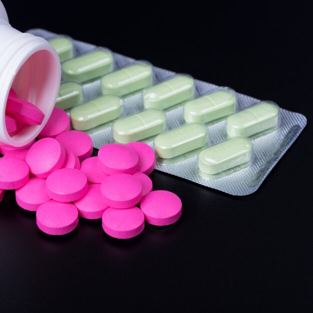 Pills are pink and blister with green pills on black background