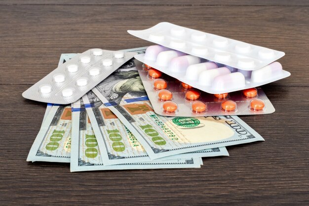 Pills in blisters and money on a wooden table