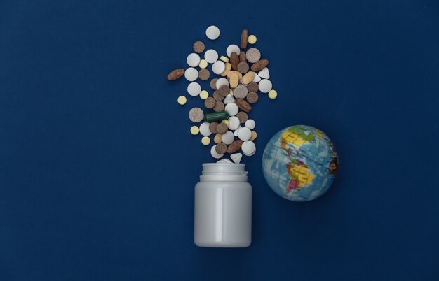 Pills bottle and globe on classic blue background. Color 2020. Top view.