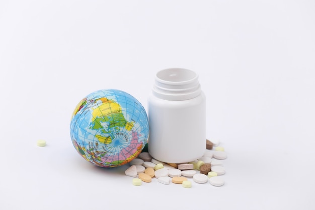 Pills bottle with globe on white background close up