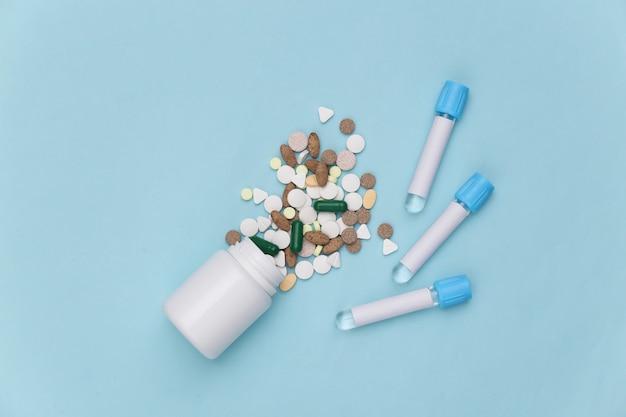 Pills bottle with Medical test tubes on blue background. Top view